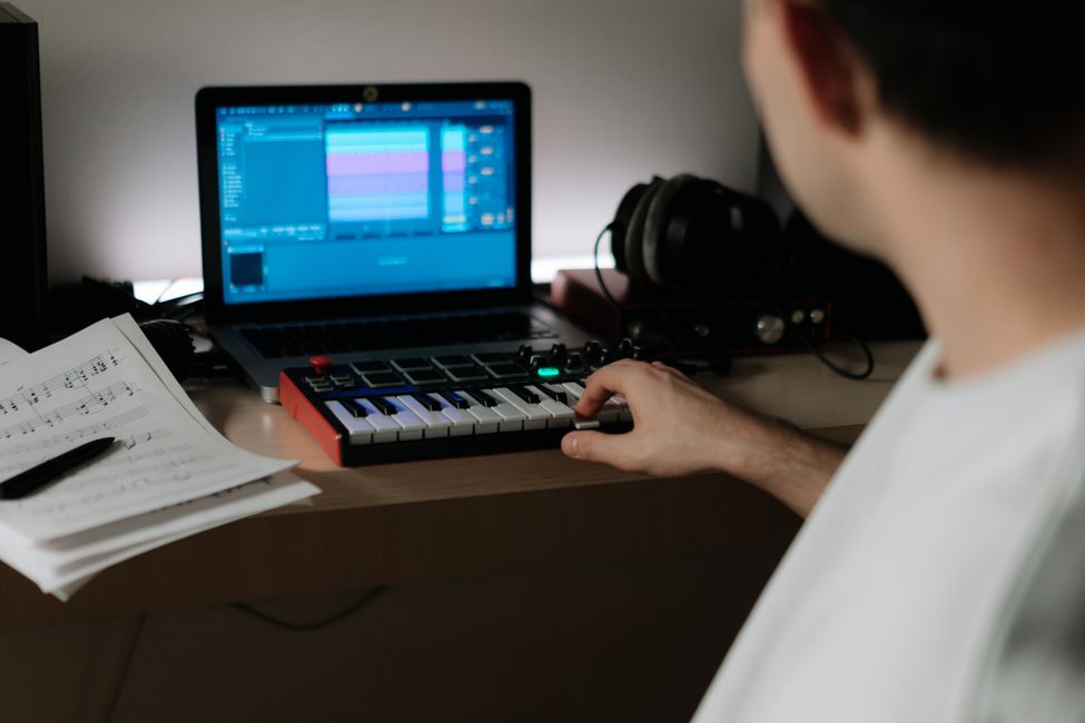 Music producer composing in a home studio with synthesizer and laptop